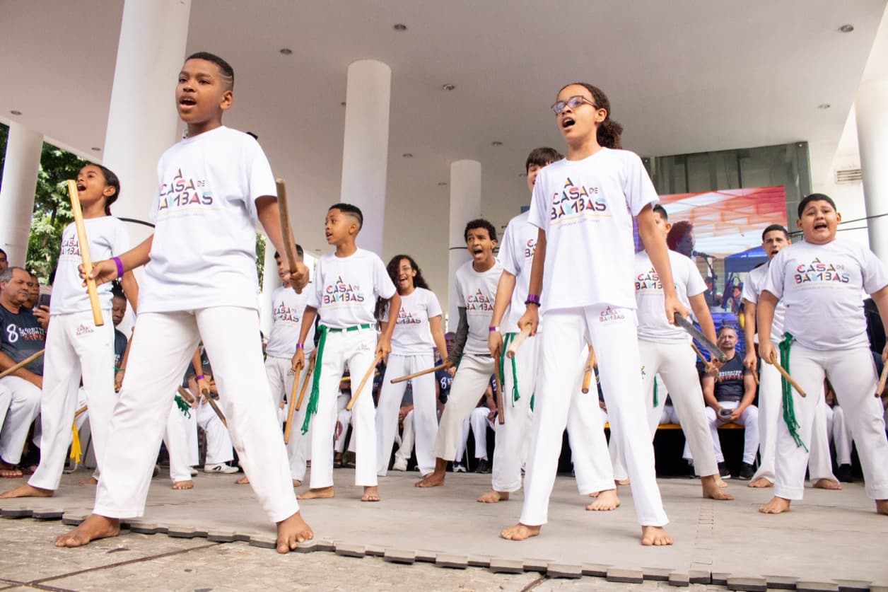 Crianças e jovens da Casa de Bambas jogando capoeira em apresentação cultural